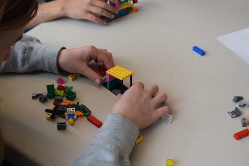 Hands placing a brick onto a part-built model