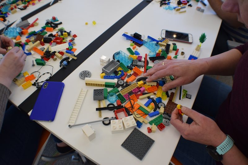Two people working over a table strewn with bricks and part-built models